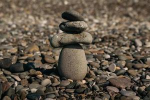 piramide di pietre sulla spiaggia di ciottoli che simboleggia stabilità, zen, armonia, equilibrio foto