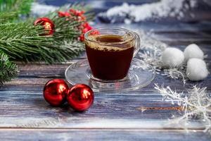 una tazza di caffè aromatico con zucchero di canna, decorazioni natalizie, rami di un albero di natale. concetto di vacanza capodanno. su uno sfondo di legno. foto