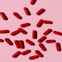 molte pillole di capsule rosse su uno sfondo colorato. integratori e medicinali per la salute foto