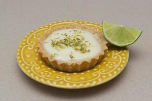 vista laterale della crostata al limone sul piatto piatto con fette di limone sul tavolo. foto