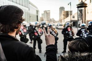 montreal, canada, 2 aprile 2015 - uomo che fa un segno di pace davanti ai poliziotti foto