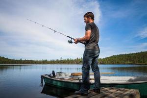 giovane adulto che pesca in un lago calmo foto