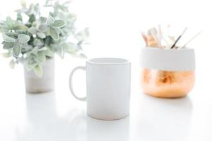tazza da caffè bianca con foglia verde per set di mock-up design vetroso isolato su bianco foto