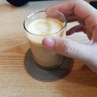 caffè al latte in un bicchiere tenuto a mano foto