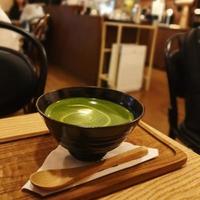 tè verde in una tazza su un vassoio su un tavolo di legno con motion blur foto