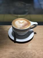 caffè al latte con una forma unica di latte su un tavolo di legno foto