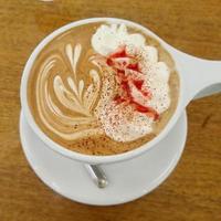 caffè latte con una punta di rosso e a forma di cuore in una tazza bianca