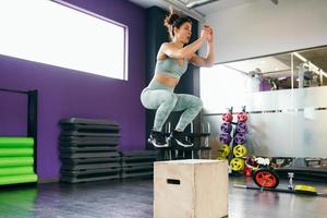 femmina caucasica che fa allenamento di salto della scatola in palestra. foto