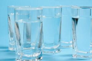 bicchieri con acqua su blu sfondo. pulito acqua concetto foto
