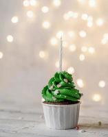 cupcakes a forma di albero di natale, circondati da decorazioni festive e luci sullo sfondo foto