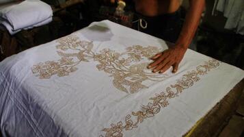 attività di realizzare batik, creare e progettare tessuto bianco utilizzando canting e cera sbattendo sul tessuto, pekalongan, indonesia, 7 marzo 2020 foto