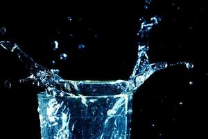 superficie dell'onda d'acqua trasparente blu chiaro con bolla di spruzzi su acqua di vetro nera. foto