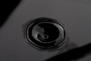 superficie dell'onda di acqua trasparente nero scuro con bolla di spruzzi sull'acqua nera. foto