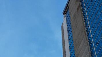un grattacielo che ha molti materiali di vetro con uno sfondo di cielo blu. l'edificio alto nell'area urbana. foto