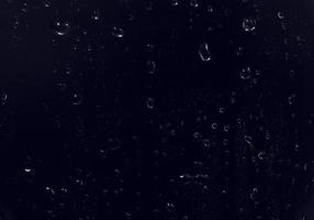 gocce d'acqua su sfondo nero. goccioline d'acqua di rugiada astratte sul vetro di una finestra per un effetto di sovrapposizione di foto o per dare un effetto fresco al modello di bevande. colpo a macroistruzione della goccia di pioggia dettagliata.
