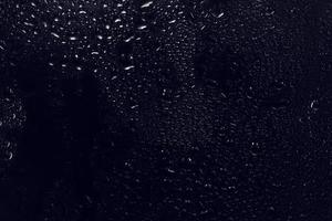gocce d'acqua su sfondo nero. goccioline d'acqua di rugiada astratte sul vetro di una finestra per un effetto di sovrapposizione di foto o per dare un effetto fresco al modello di bevande. colpo a macroistruzione della goccia di pioggia dettagliata.