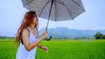 le donne asiatiche viaggiano rilassarsi durante le vacanze. le donne in piedi regge un ombrello sotto la pioggia felici e si godono la pioggia che sta cadendo. viaggiare in campagna, risaie verdi, viaggiare in thailandia. foto