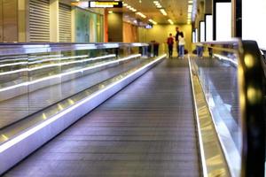 la luminosa corsia di trasporto dell'aeroporto trasporta i passeggeri sfocati. foto