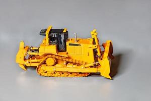 modello giocattolo di un bulldozer da costruzione su uno sfondo grigio chiaro. foto