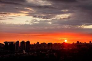 sagome di città notturne, paesaggio estivo della città mattutina sullo sfondo di un'alba arancione brillante. foto