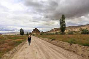 la donna turistica torna a casa su una strada sterrata e sabbiosa. foto