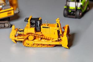 modello giocattolo di un bulldozer da costruzione su uno sfondo grigio chiaro. foto