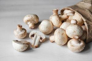 funghi champignon in sacchetto di carta su un tavolo di legno bianco foto