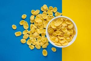 cornflakes in ciotola bianca su sfondo blu e giallo foto