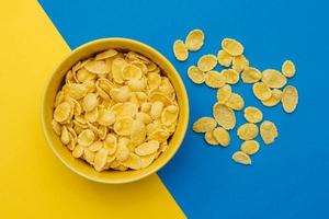 cornflakes in ciotola gialla su sfondo giallo e blu foto
