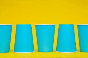 posizionamento di bicchieri di carta blu in linea su sfondo giallo