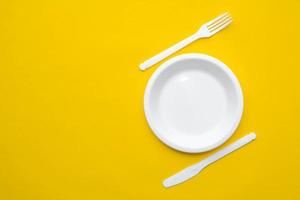 forchetta, coltello e piatto di plastica bianchi su sfondo giallo