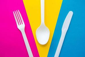 forchetta, coltello e cucchiaio in plastica bianca su sfondo multicolore