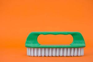 spazzola di pulizia verde su sfondo arancione foto