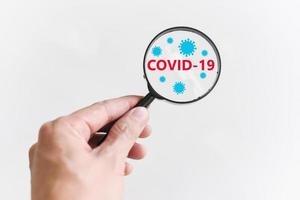 covid-19 concetto di ricerca e trattamento - la mano del medico tiene in mano una lente d'ingrandimento per il vaccino di ricerca coronavirus covid-19 virus foto