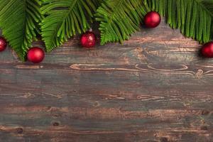 foglia di pino natalizio con decorazione a pallina su tavola di legno foto