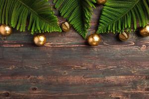 foglia di pino natalizio con decorazioni dorate su tavola di legno foto