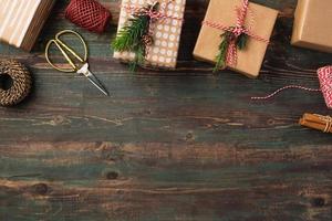 confezione regalo natalizia fatta a mano con decorazioni in carta marrone con abete di pino su tavola di legno foto