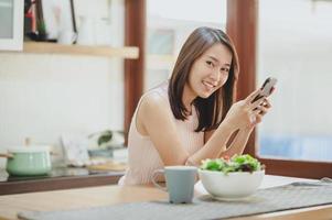 donna asiatica che usa lo smartphone a casa