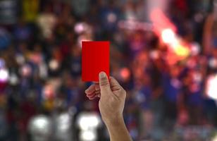 l'arbitro alza la mano e mostra un cartellino rosso in una partita di calcio. foto