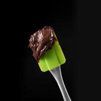 Close up spatola e cioccolato fuso su sfondo nero foto
