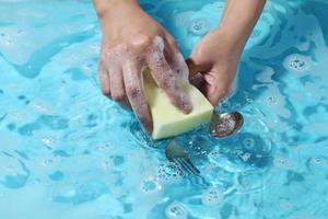 cucchiaio e forchetta di lavaggio della mano della donna in acqua. foto
