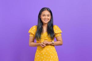 la giovane donna asiatica sorridente tiene la mano insieme e si sente ottimista su sfondo viola foto