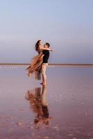 ragazza e un ragazzo sulla riva di un lago salato rosa foto