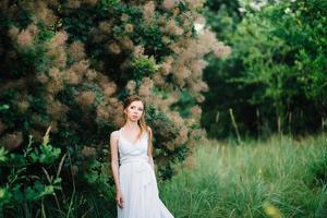 ragazza felice in un abito lungo turchese in un parco verde foto