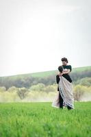 lo sposo in abito marrone e la sposa in abito color avorio in campo verde foto
