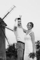 ragazza con un prendisole bianco e un ragazzo con una camicia bianca durante una passeggiata al tramonto con un bouquet foto