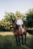 ragazzo in camicia bianca a passeggio con cavalli marroni foto