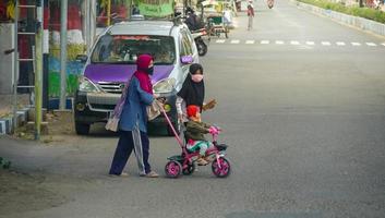 indonesia 2021. madre con le sue figlie che attraversano l'autostrada foto