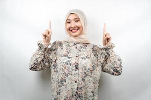 bella giovane donna musulmana asiatica sorridente sicura di sé, entusiasta e allegra con le mani rivolte verso l'alto presentando qualcosa, guardando la telecamera isolata su sfondo bianco, concetto pubblicitario foto