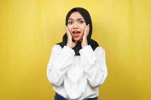 bella giovane donna musulmana asiatica scioccata, sorpresa, espressione wow, con le mani che tengono la guancia, isolata su sfondo giallo foto